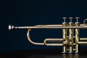 portion of a brass trumpet on a dark blue background